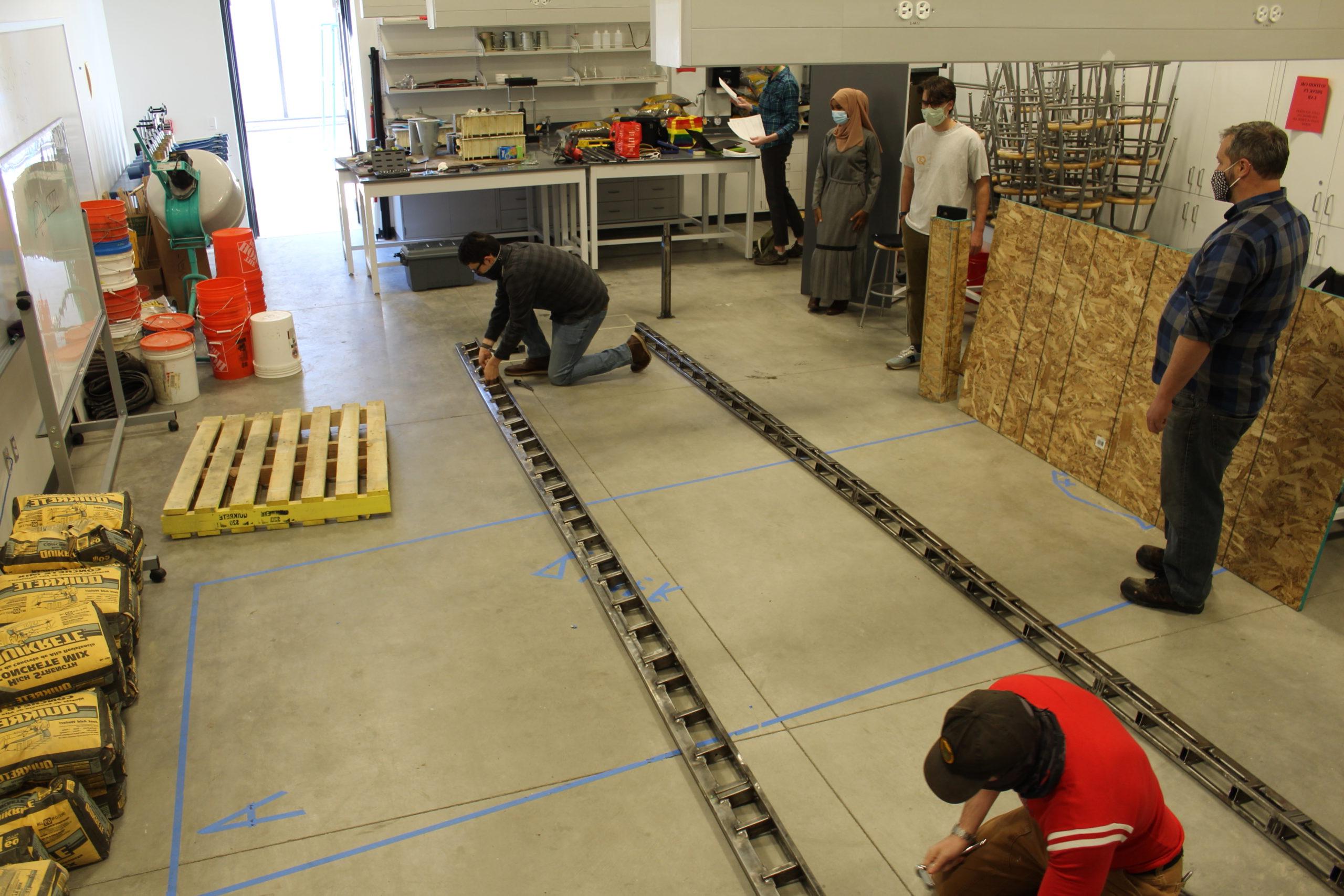 Individuals working on a long metal piece