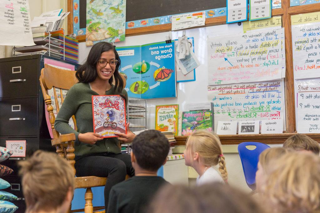 MSU Denver student Idalee Nunez reading a book to young children in a classroom.