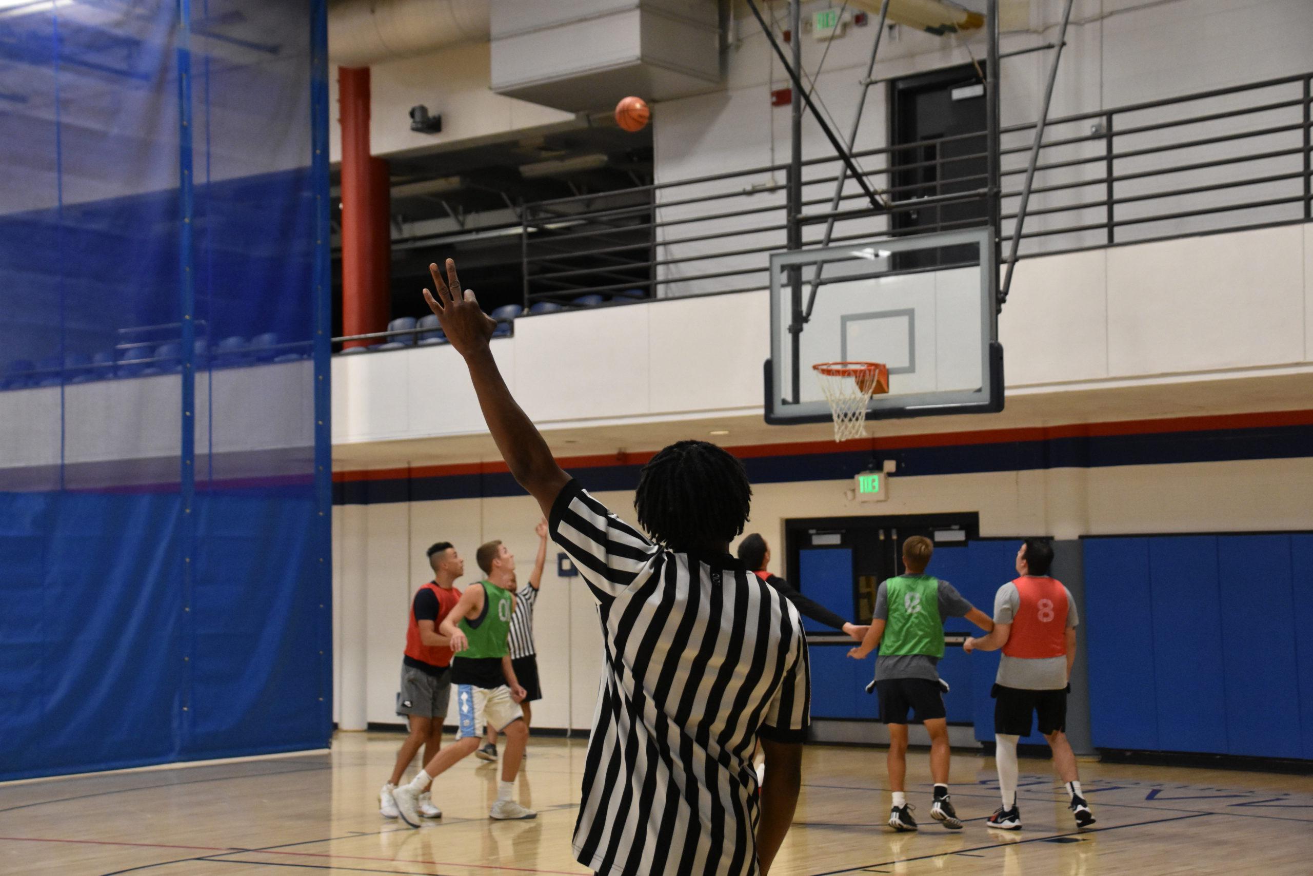 basketball official showing a 3 point attempt