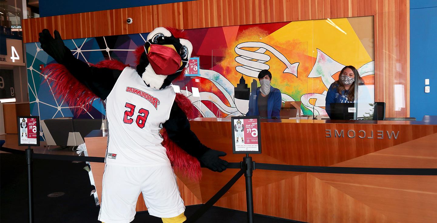Rowdy in the main lobby of the Jordan Student Success Building, wearing a mask with the welcome staff.