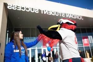 student employee giving Roadrunner mascot a high five in front of JSSB.