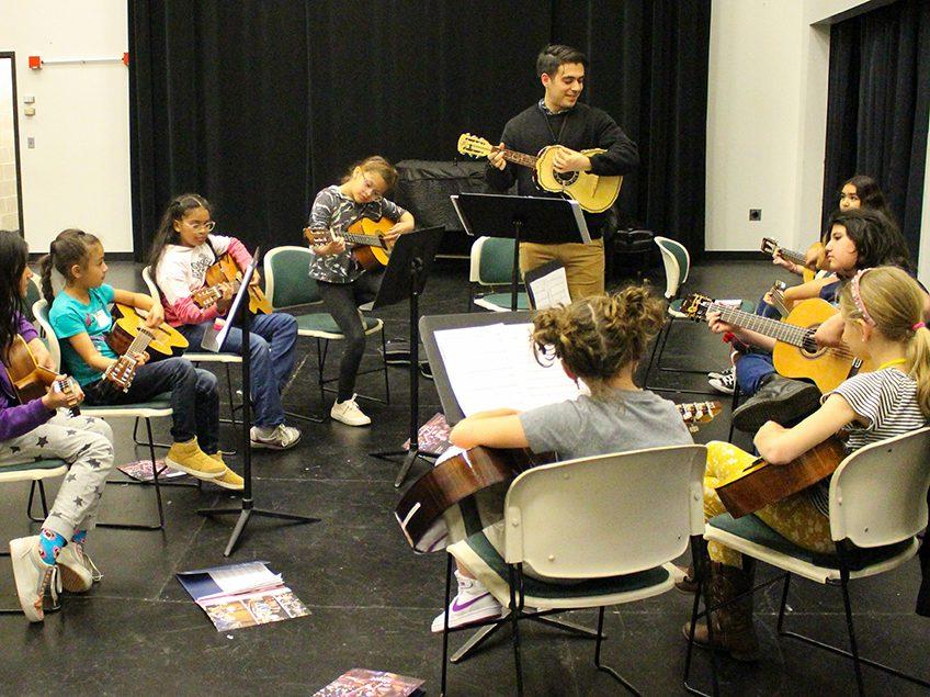 group of children learning guitar