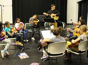 Group of kids learning guitar